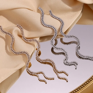 Boucles d'oreilles vagues en S plaquées or 18 carats avec zircons blancs sur satin beige