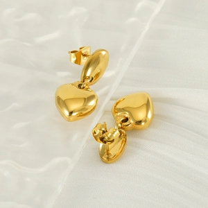 Boucles d'oreilles pendantes cœur doré sur tissu plissé blanc au style luxueux