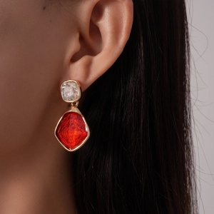 Dettaglio di orecchini vintage con gemme di resina rossa e cristalli su modella