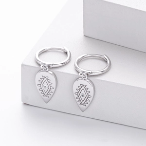 Macro shot of silver drop earrings featuring engraved eye pattern and small zircon stone