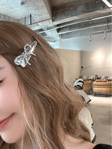 Gros plan d'une barrette à strass en forme de nœud sur les cheveux bouclés d'un mannequin