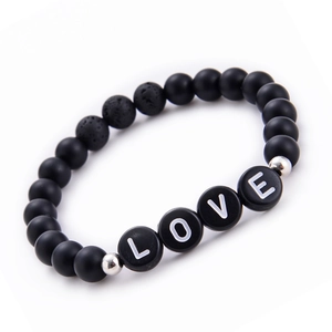 Detail of matte black stone beads and LOVE alphabet charms on a beaded couple bracelet