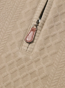 Detailed close-up of textured jacquard knit fabric and metal zipper with leather puller