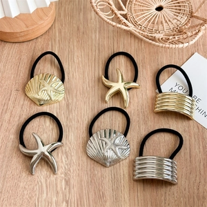 Close-up of gold and silver metal hair ties with starfish and shell charms on a desk
