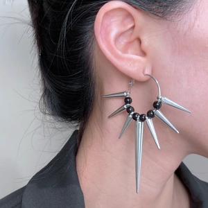 Silver spike hoop earrings with black beads in a punk gothic style on female model