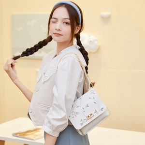Fashionable white chain shoulder bag featuring delicate floral embroidery and metal lock