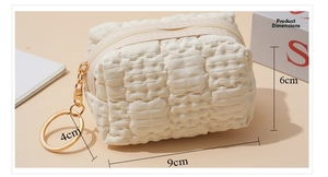Detail view of cream waffle pattern coin purse with golden chain and ring keychain