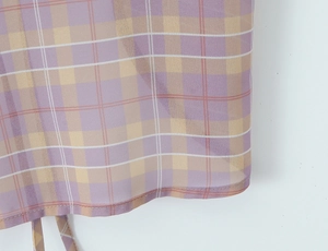 Detailed close-up of purple and yellow plaid chiffon fabric with fine hem stitching
