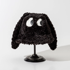 Détail du chapeau bob en peluche noire avec motif gros yeux et texture en fourrure