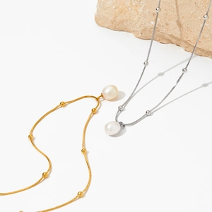 Elegant pearl pendant necklaces in gold and silver finish on a minimalist display