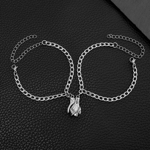 Matching silver magnetic handholding couple bracelets on premium black leather surface