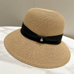Detailed close-up of woven straw sun hat texture with elegant black ribbon and metal buckle