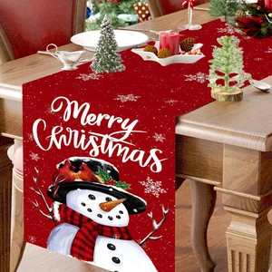 Red Christmas table runner featuring snowmen and birds on a festive wooden dinner table