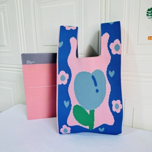 Detailed close-up of blue knit tote bag with pink tulip and green leaf floral pattern