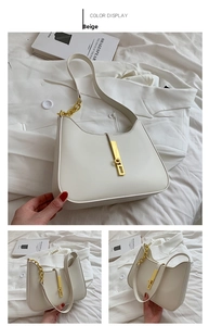 Detail view of beige saddle bag with gold hardware and elegant chain strap accents