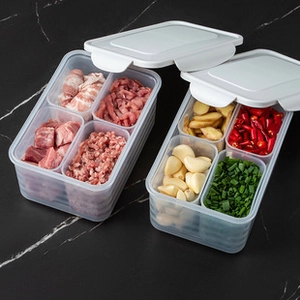 Detail of four-compartment food prep storage boxes with white lids on marble surface