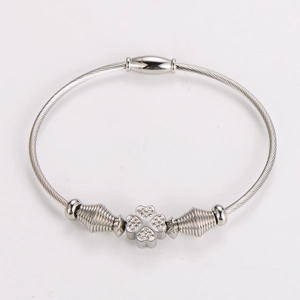 Detailed shot of silver cable wire bracelet featuring a clover charm with small crystals