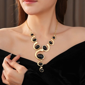 Close-up of gold geometric necklace with black oval gemstones on model neckline
