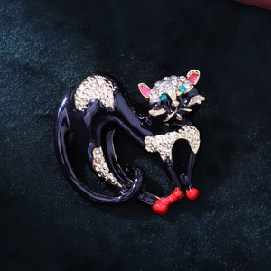Detailed close-up of a black enamel cat brooch with sparkling rhinestones and a red bow