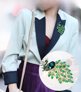 Macro shot of green crystal peacock brooch with intricate gold alloy settings