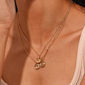 Detailed close-up of a three-layer gold stainless steel necklace with city pendants