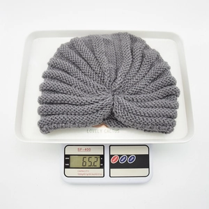 Detail view of a gray knit turban hat on a digital scale showing a weight of 65.2g