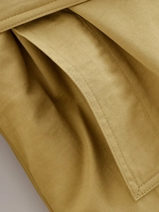 Macro view of mustard yellow twill fabric showing fine stitching and pocket detail texture