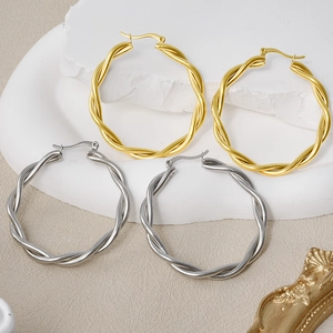 Detailed view of large twisted hoop earrings in gold and silver finish on stone
