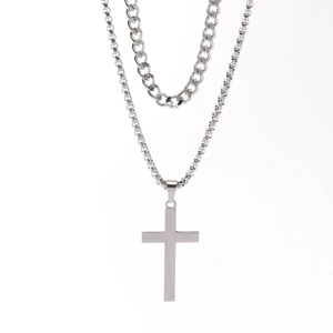 Detail of a double-layer men's stainless steel necklace with cross pendant and cuban links