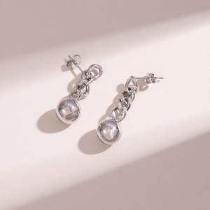 Detailed close-up of silver steel chain earrings with large metal sphere drops