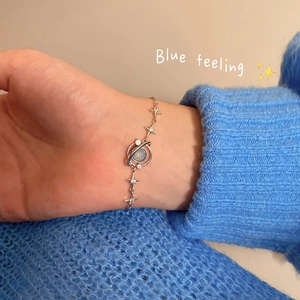 Detail of silver planet bracelet with blue stone and zircons on a model's wrist
