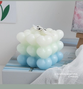 Macro shot of gradient heart-shaped bubble candle with white ribbon and chic packaging