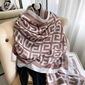 Elegant houndstooth silk scarf in brown and white draped over a minimalist chair