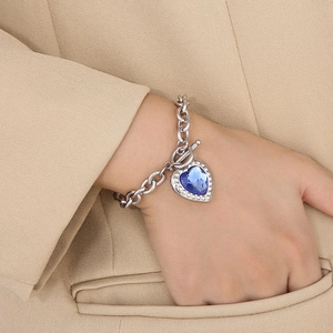 Detail of silver OT buckle bracelet with a heart-shaped blue stone on khaki fabric