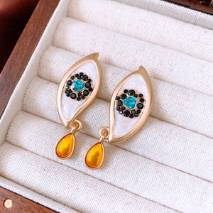 Detail of vintage evil eye gold earrings with blue resin drip and sparkling rhinestones