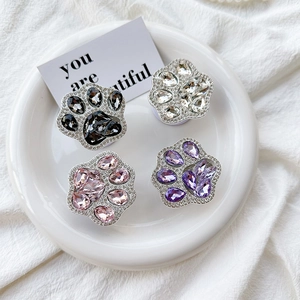 Close-up of four rhinestone cat paw phone socket stands in pink, gray, and purple colors