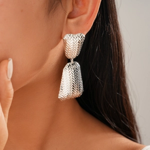 Detail of silver textured hoop earrings with woven metallic finish on a female model