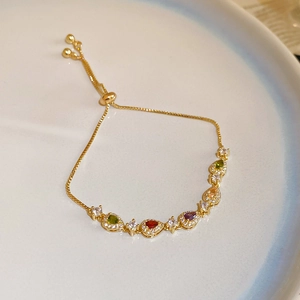 Close-up of a gold bracelet featuring multi-colored teardrop gems and adjustable drawstring