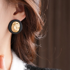 Close-up of vintage round earrings with black outer ring and textured gold metal core