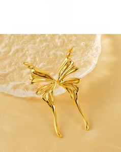 Detail of golden butterfly wing earrings with polished finish on gold satin background