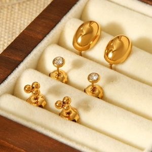 Macro shot of three pairs of gold-plated titanium earrings with zircon in a jewelry box