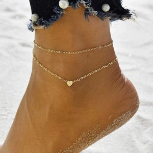 Elegant gold double layered heart anklet with letter A pendant on beach sand