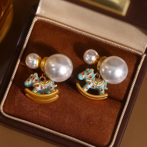 Rocking horse enamel earrings with pearls and gold metal on a velvet jewelry display case