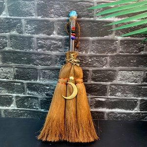 Close-up of decorative brown witch broom with natural crystals and crescent moon charms