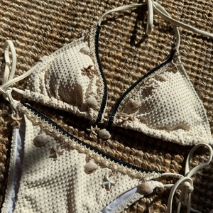 Detail view of white bikini with textured fabric and seashell starfish charms