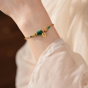 Détail du bracelet vintage doré avec malachite verte et pendentif brillant sur modèle