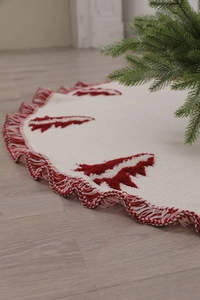 Close-up of white knitted Christmas tree skirt with red tree patterns and fringed edges