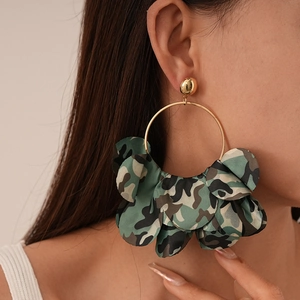 Close-up of a model wearing large camouflage fabric petal earrings with gold rings