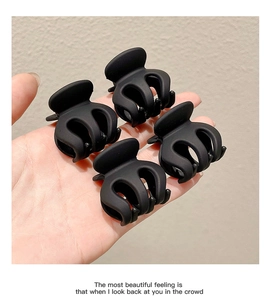 Close-up of four matte black claw clips with elegant hollow five-claw design and metal springs