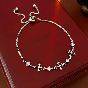 Elegant silver zircon cross bracelet with adjustable slide clasp on a wooden jewelry box